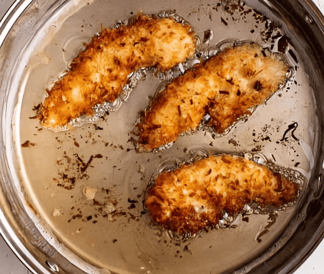 fried coconut chicken tenders in oil.