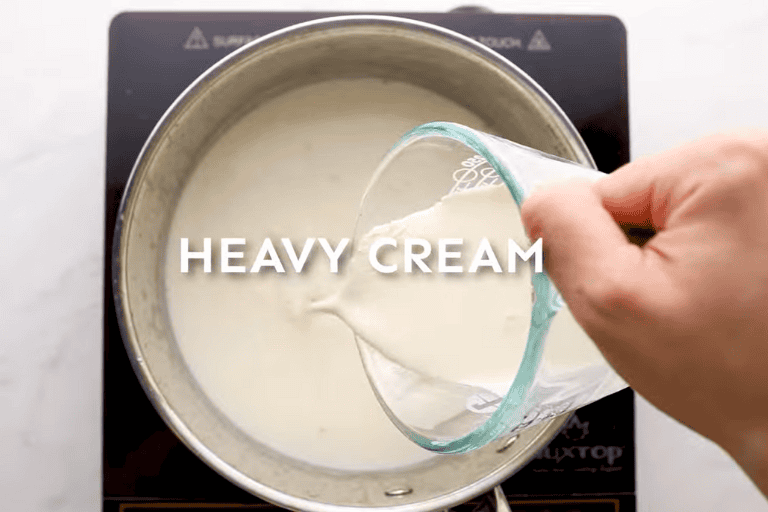 Heavy cream being added to a pot of milk.