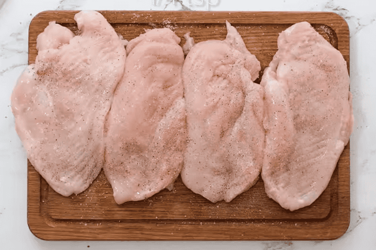 Four seasoned chicken breasts on a chopping board to make chicken bryan copycat recipe.