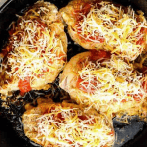 Taco stuffed chicken topped with salsa and shredded cheese in a skillet.