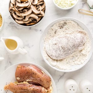 dredging a chicken breast in seasoned flour.