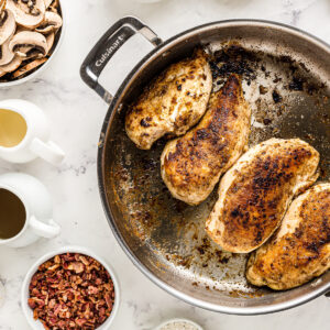 4 seared chicken breasts in a pan.