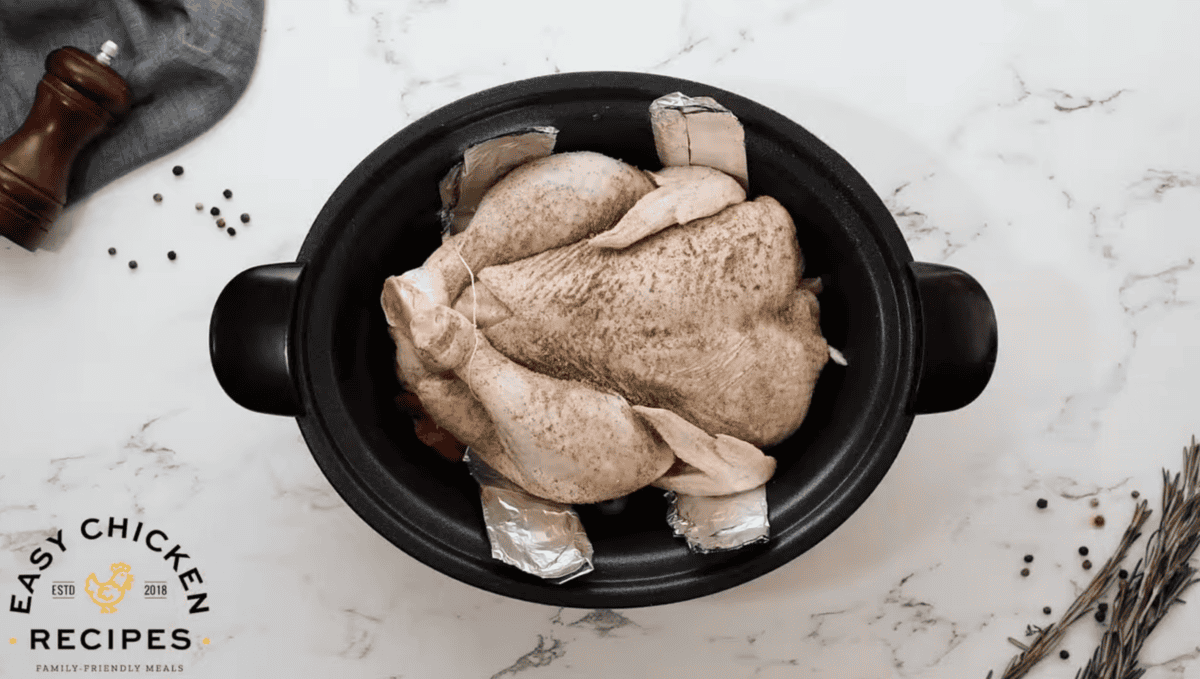 A raw chicken is placed in a slow cooker. 