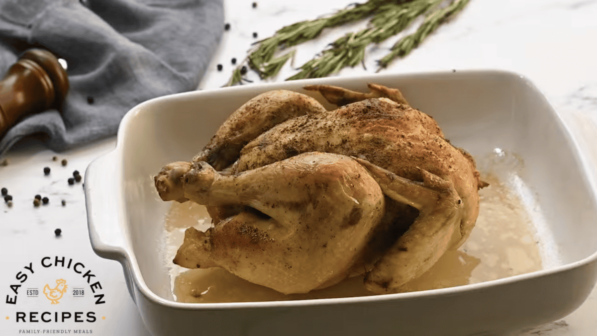 A cooked chicken is presented in a white baking dish. 