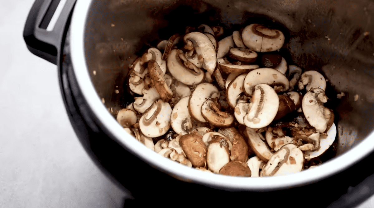 Mushrooms, onions and garlic are being sauteed. 