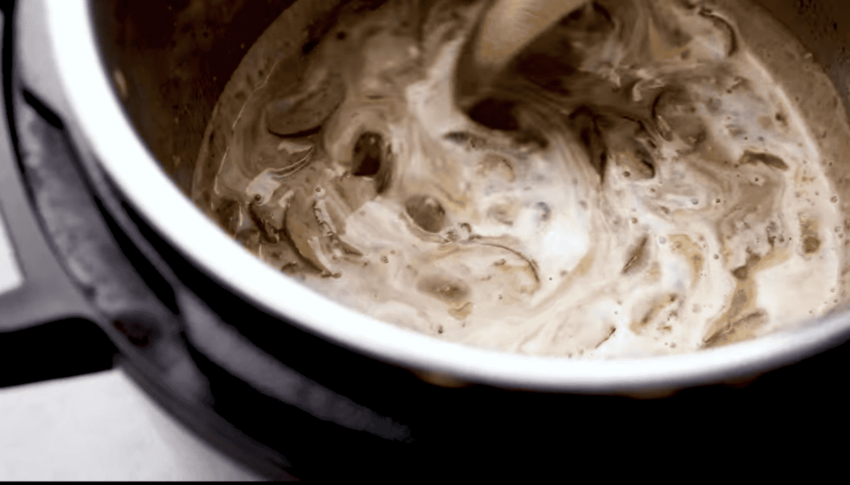 A creamy marala mixture is stirred in the instant pot. 