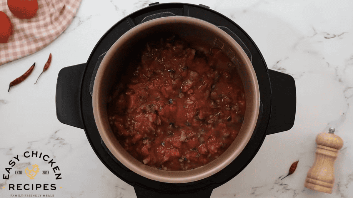 Salsa and chicken broth is poured on top of raw chicken in an Instant Pot.