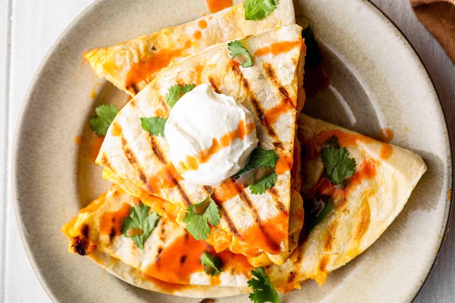 plate of stacked buffalo chicken quesadillas with sour cream