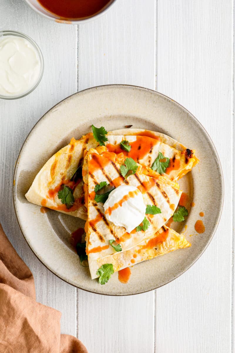 plate of stacked buffalo chicken quesadillas with sour cream