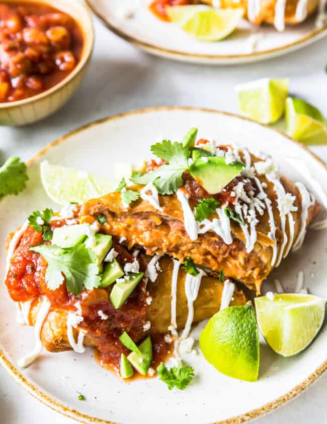 mexican enchiladas on a plate with guacamole and salsa.