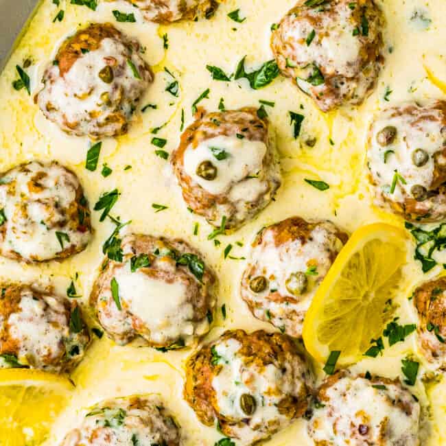 up close chicken piccata meatballs in sauce on serving dish