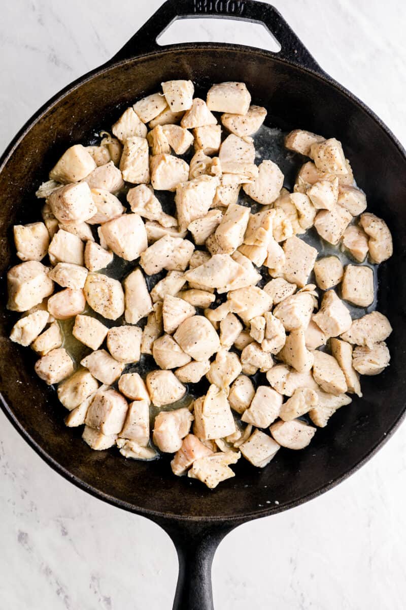 chicken chunks cooking in cast iron skillet