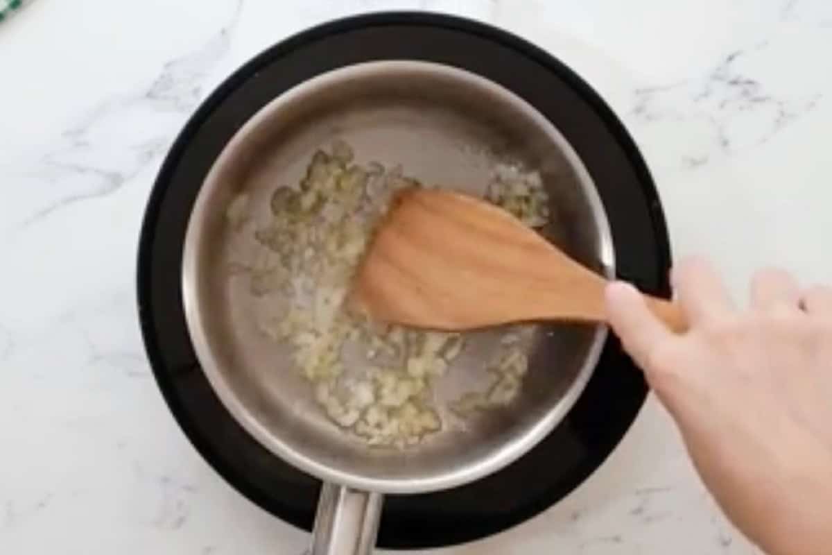 sautéeing garlic, onion, and ginger in a saucepan with a wooden spatula.