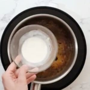 adding a cornstarch slurry to orange sauce.