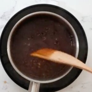 thickened orange sauce in a saucepan with a wooden spatula.