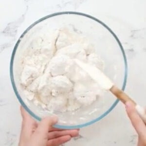 tossing egg-coated chicken pieces in flour and cornstarch with a rubber spatula.