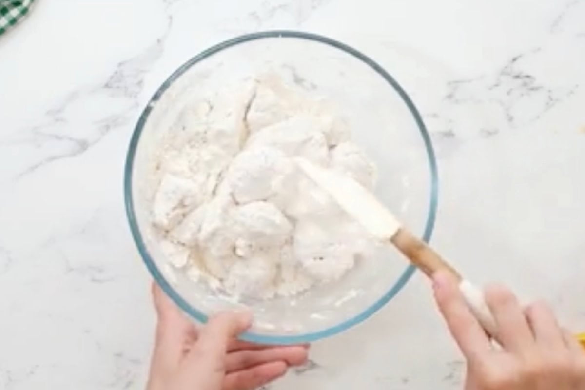 tossing egg-coated chicken pieces in flour and cornstarch with a rubber spatula.