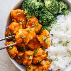 overhead view of a serving of crispy orange chicken in a bowl with rice and broccoli.