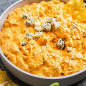 crockpot buffalo chicken dip in a white bowl with blue cheese.