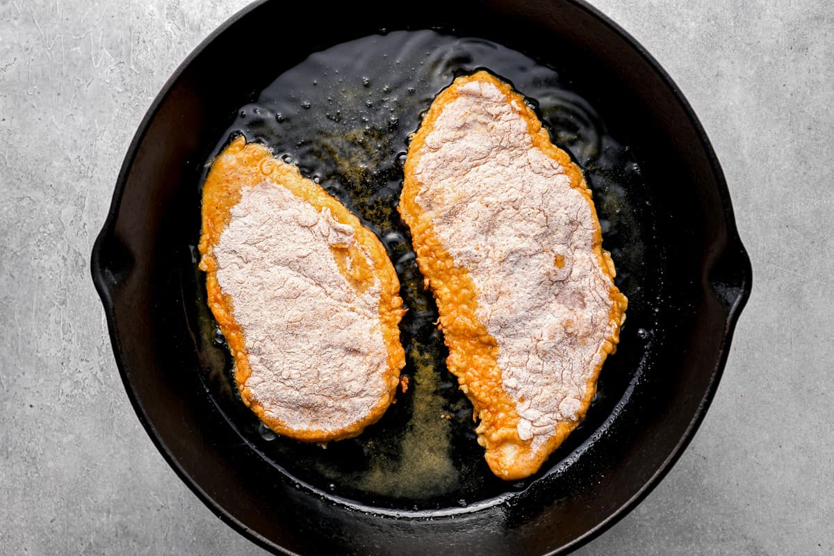 chicken frying in a cast iron pan.