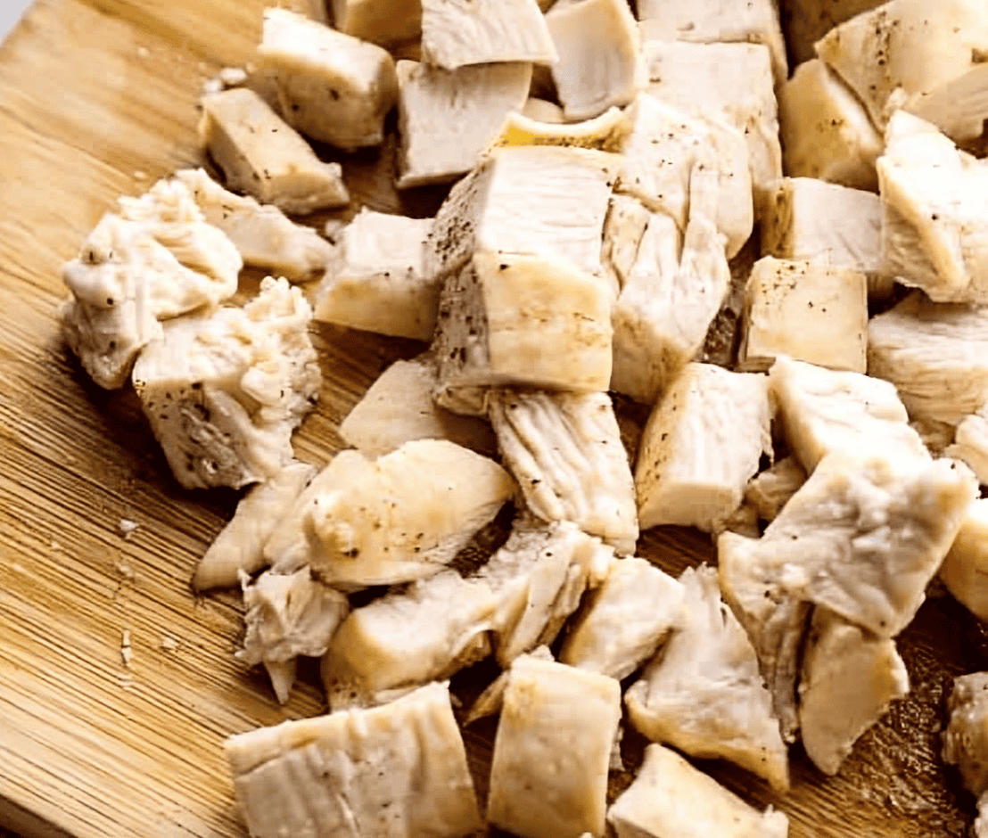 chopped cooked chicken breast on a cutting board.