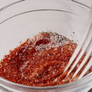 Seasoning for spanish chicken and rice being mixed with a fork in a bowl