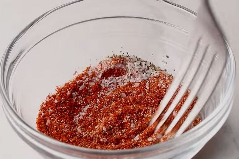 Seasoning for spanish chicken and rice being mixed with a fork in a bowl