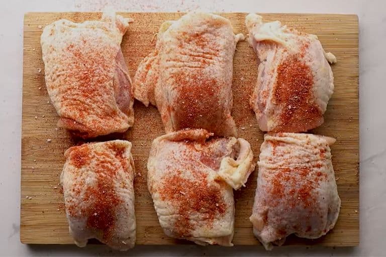 Seasoned chicken thighs on a wooden chopping board