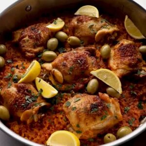 Spanish chicken and rice with olives, lemon wedges, and parslein a skillet