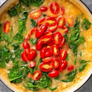 adding tomatoes and spinach to tuscan chicken.