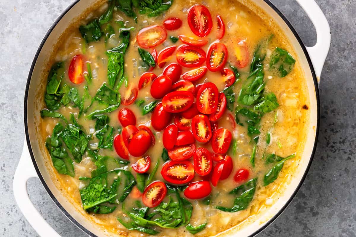 adding tomatoes and spinach to tuscan chicken.