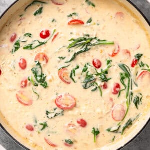 cream sauce with spinach and tomatoes in a skillet.