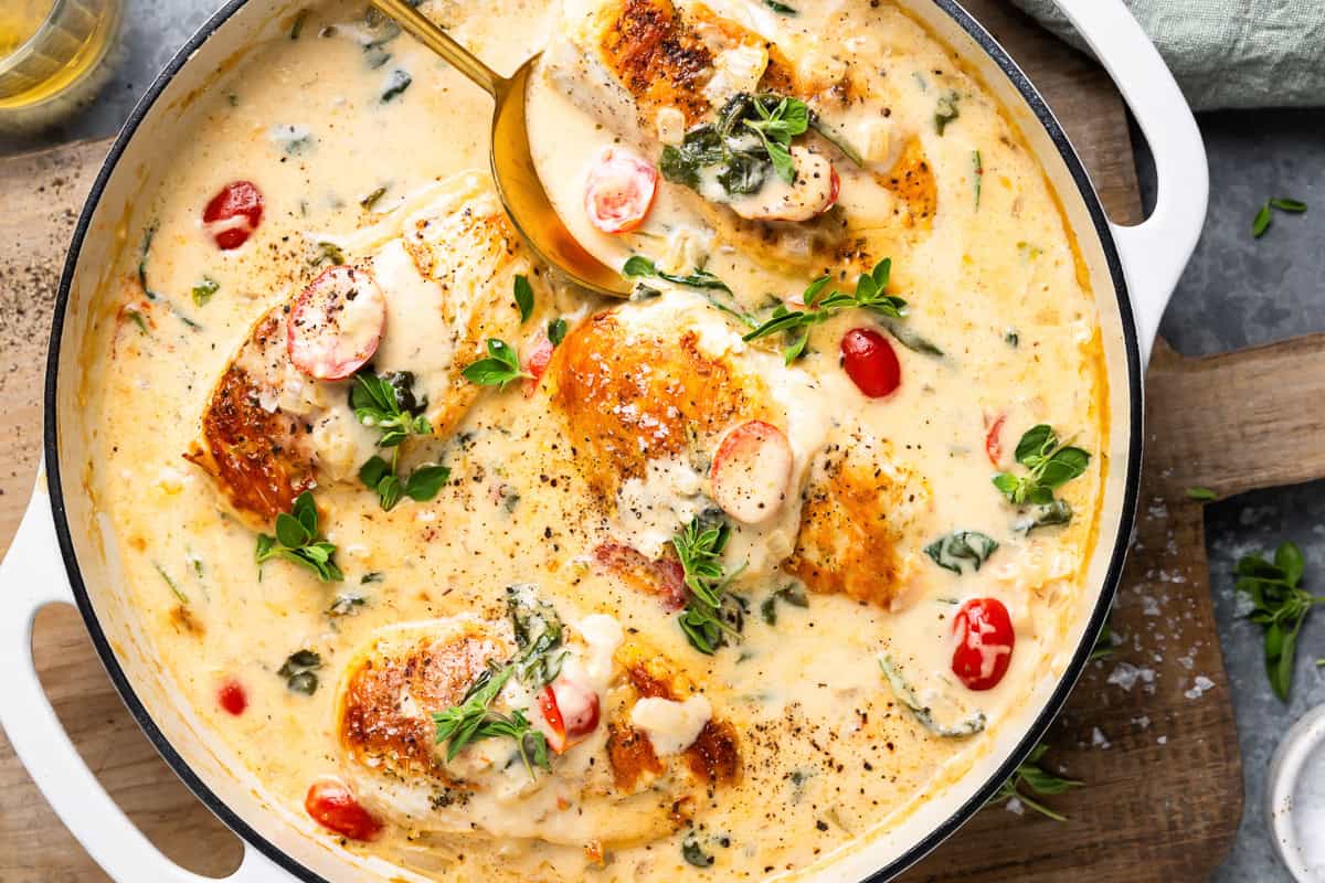 overhead view of tuscan chicken in a skillet with a spoon.