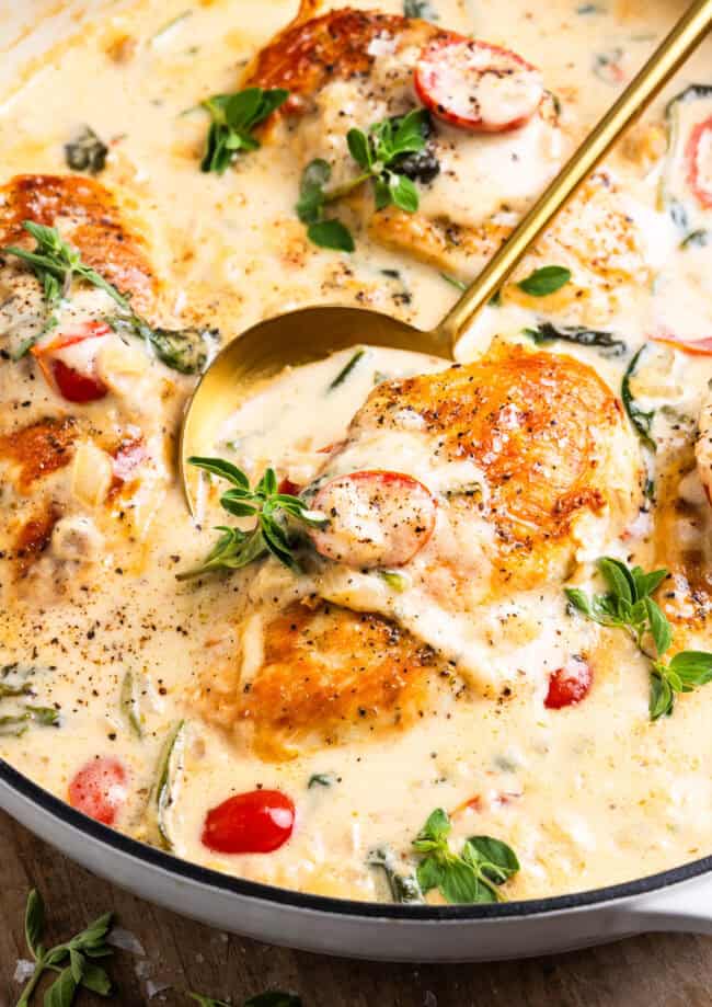 closeup of a skillet full of tuscan chicken with spoon.