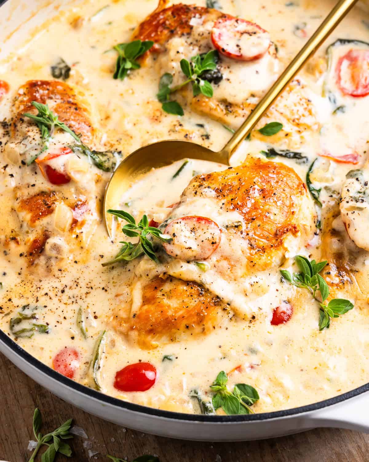 closeup of a skillet full of tuscan chicken with spoon.