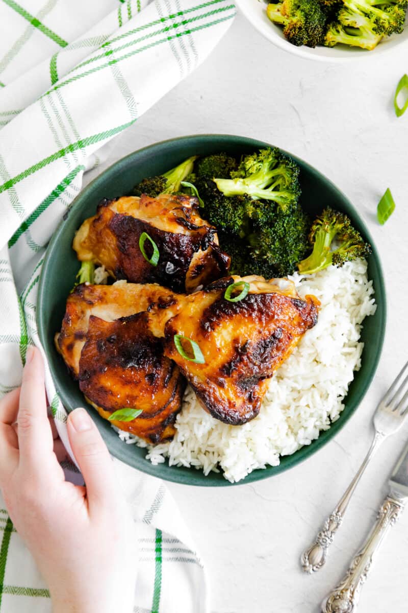 hand on plate of air fryer honey mustard chicken with rice and broccoli