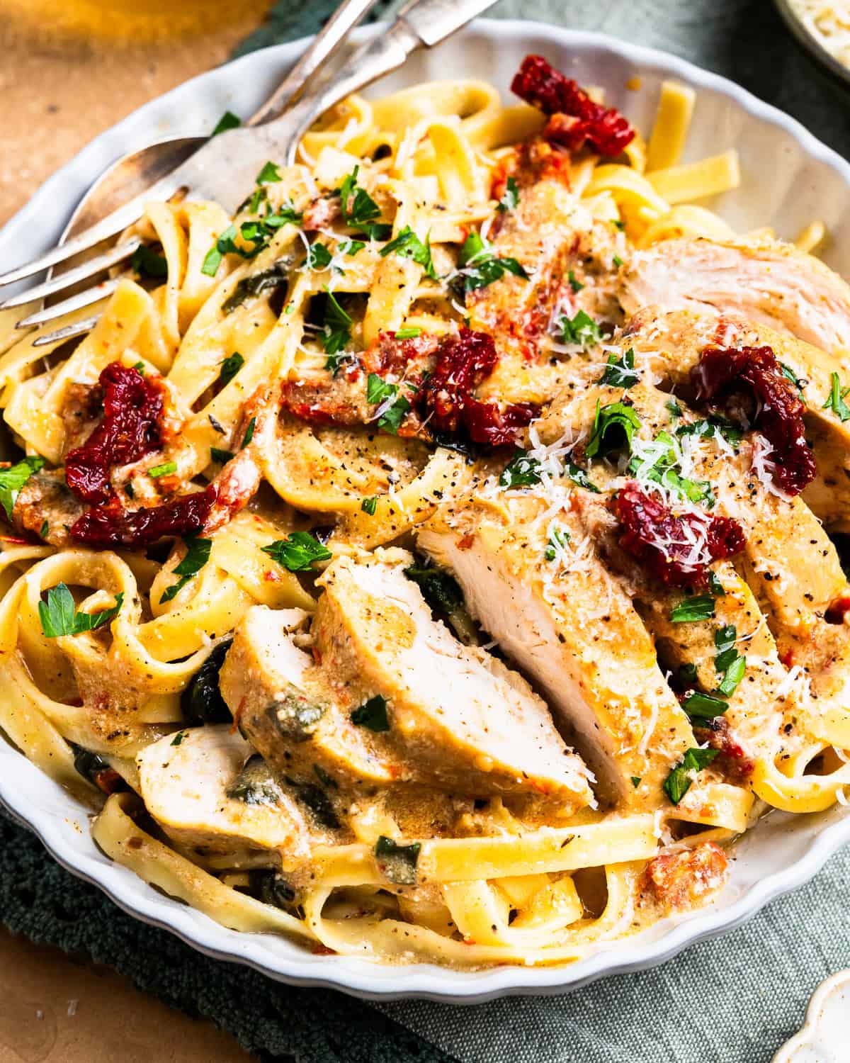 sliced tuscan chicken on a white plate with pasta.