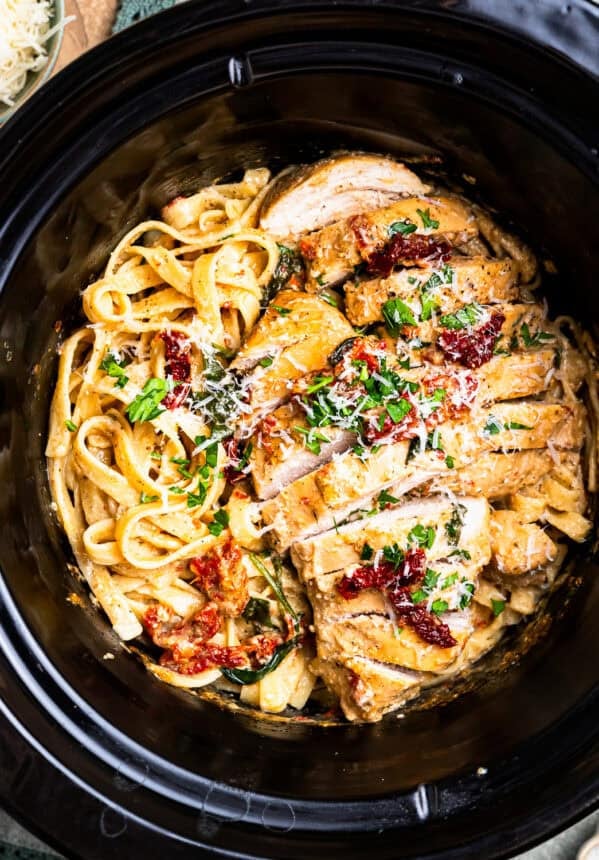 overhead view of sliced tuscan chicken and pasta in a crockpot.