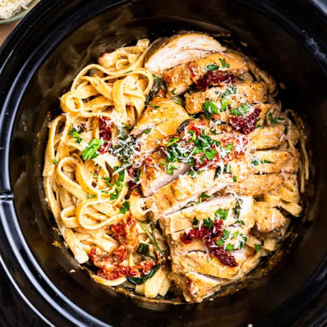 overhead view of sliced tuscan chicken and pasta in a crockpot.