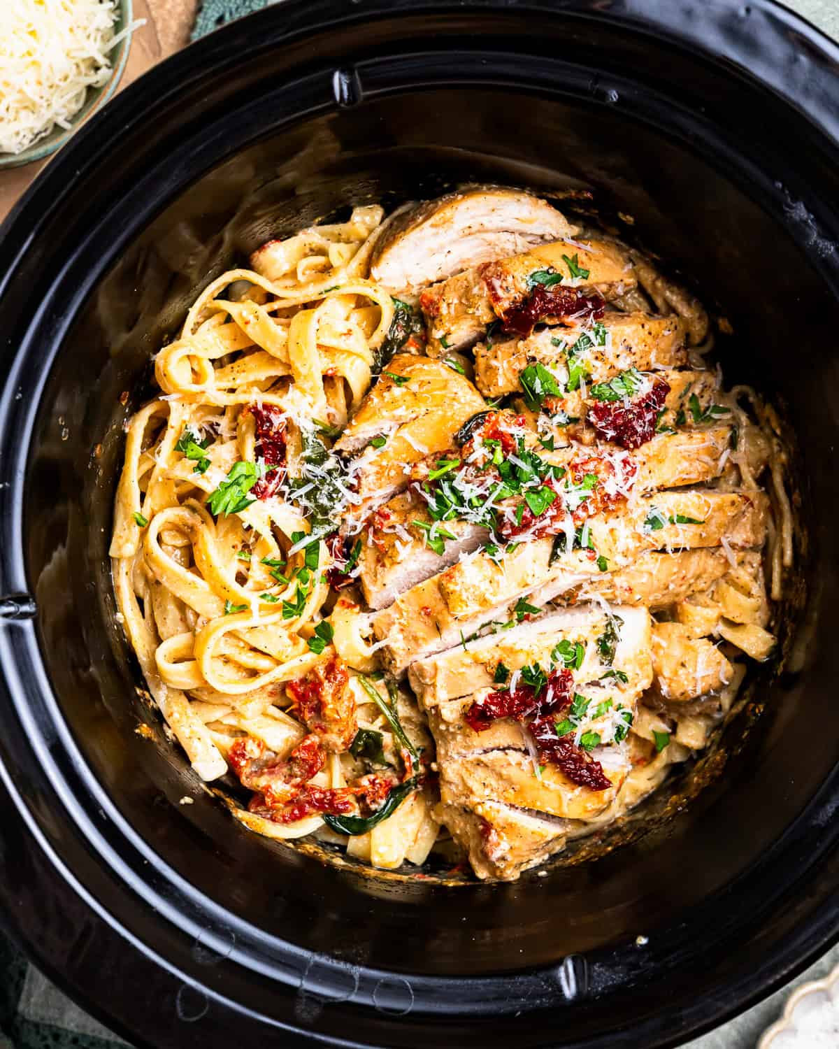 overhead view of sliced tuscan chicken and pasta in a crockpot.