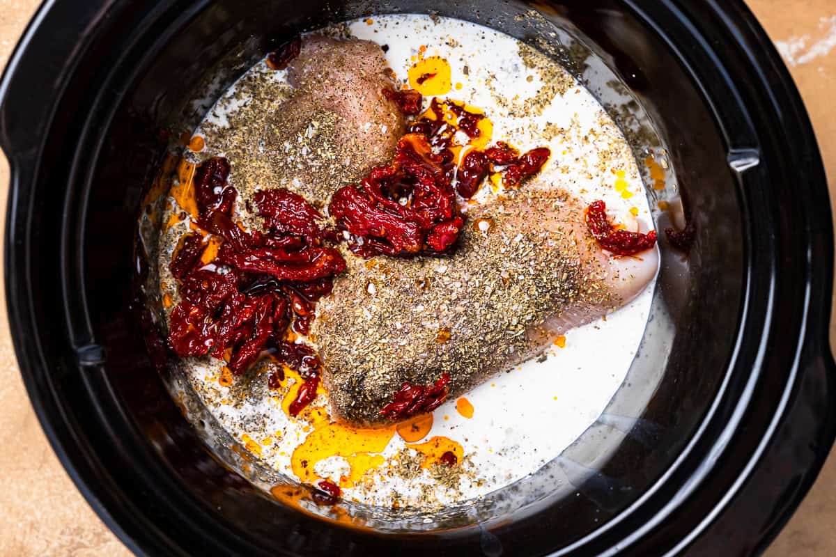 seasoned chicken breasts, cream, and sun-dried tomatoes in a crockpot.