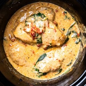 cooked chicken breasts in a creamy orange sauce in a crockpot.