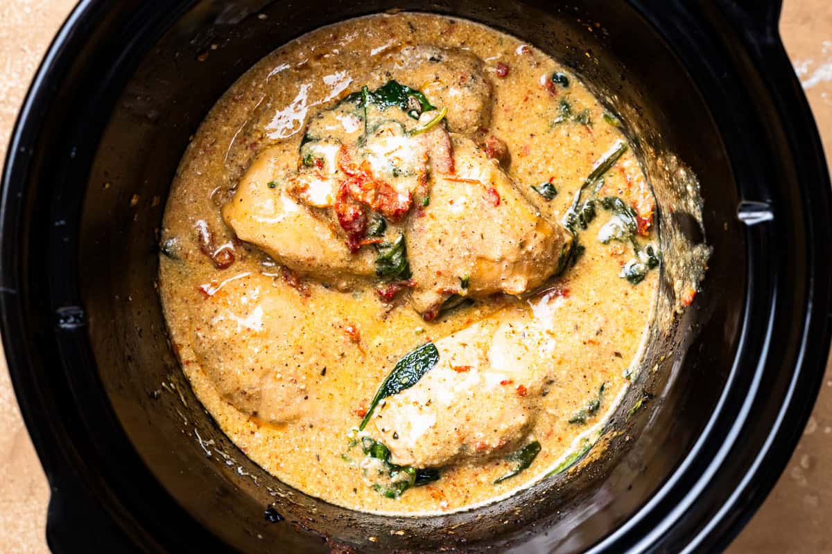 cooked chicken breasts in a creamy orange sauce in a crockpot.