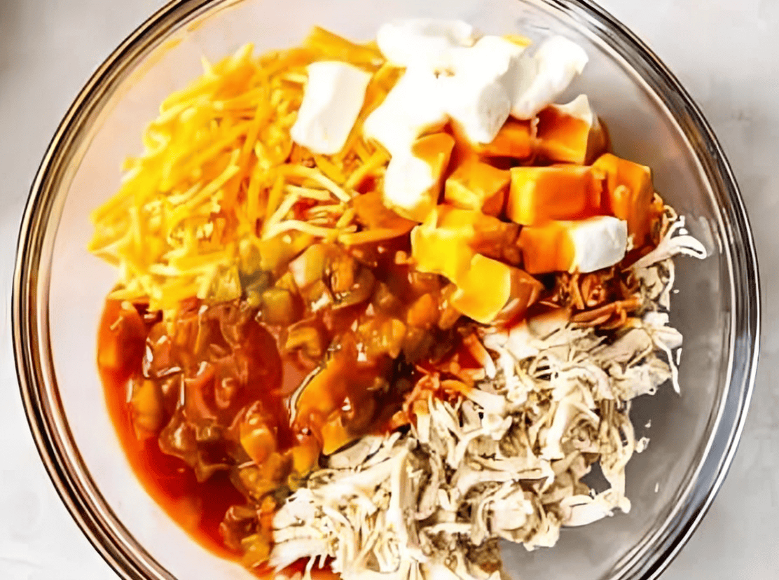 ingredients for buffalo chicken enchilada filling in a glass bowl.