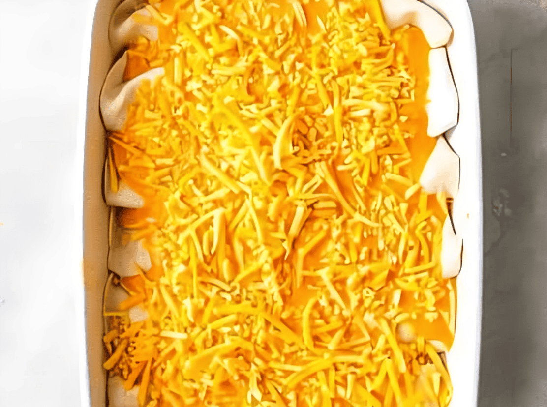 cheese-topped buffalo chicken enchiladas in a baking dish.