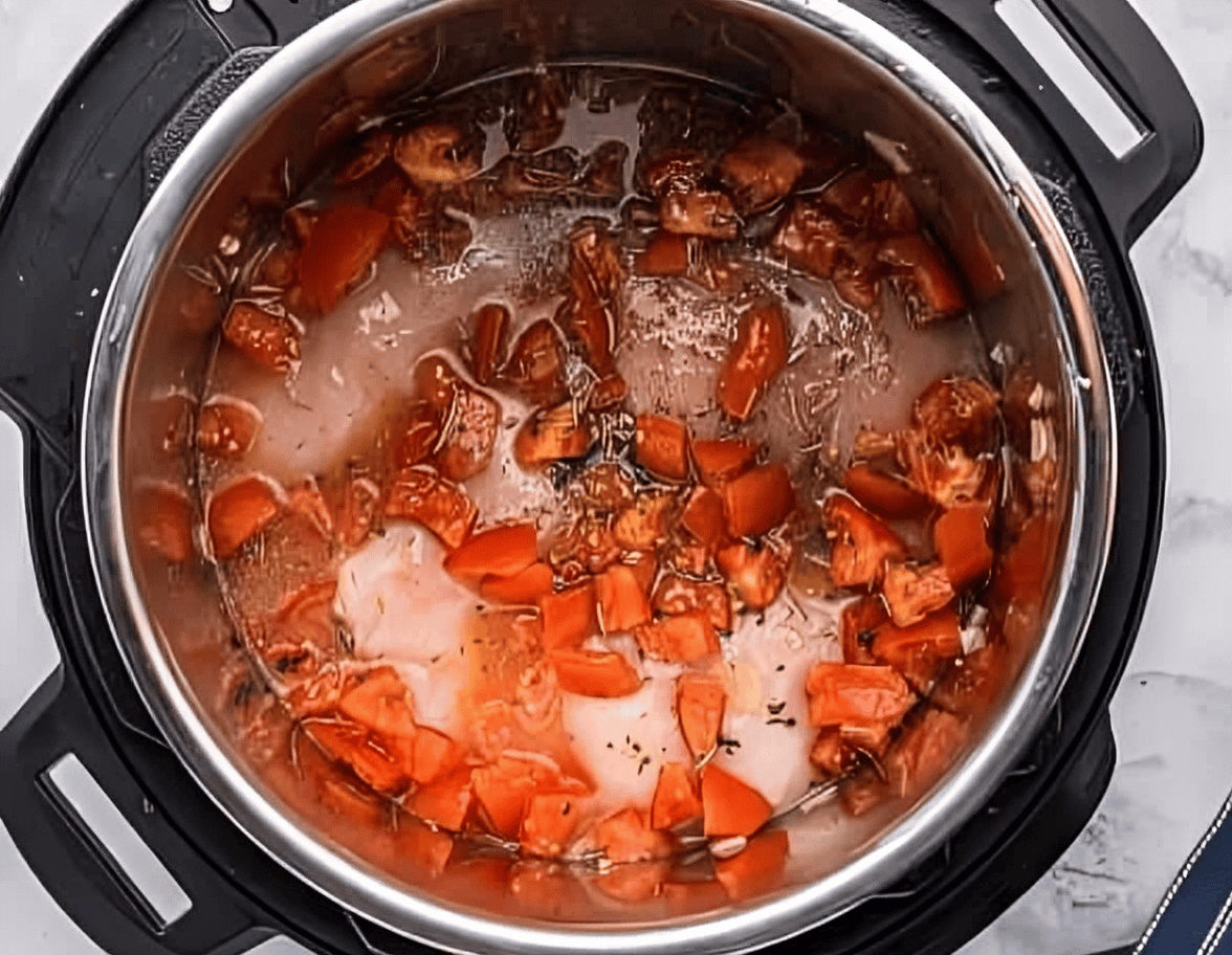 raw chicken breasts topped with seasonings, broth, and chopped tomatoes in an instant pot.