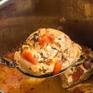 lifting an balsamic chicken breast from an instant pot with a serving spoon.