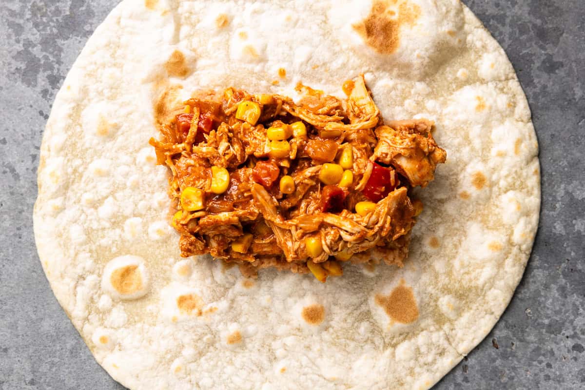 chicken filling spread over beans on a tortilla.