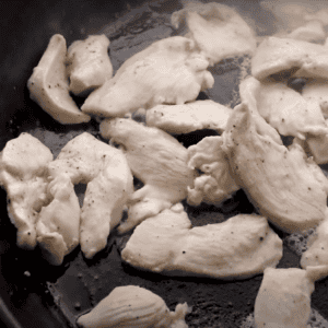 cooking sliced chicken in a pan.