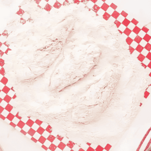 battered chicken tenders in a pile of flour.